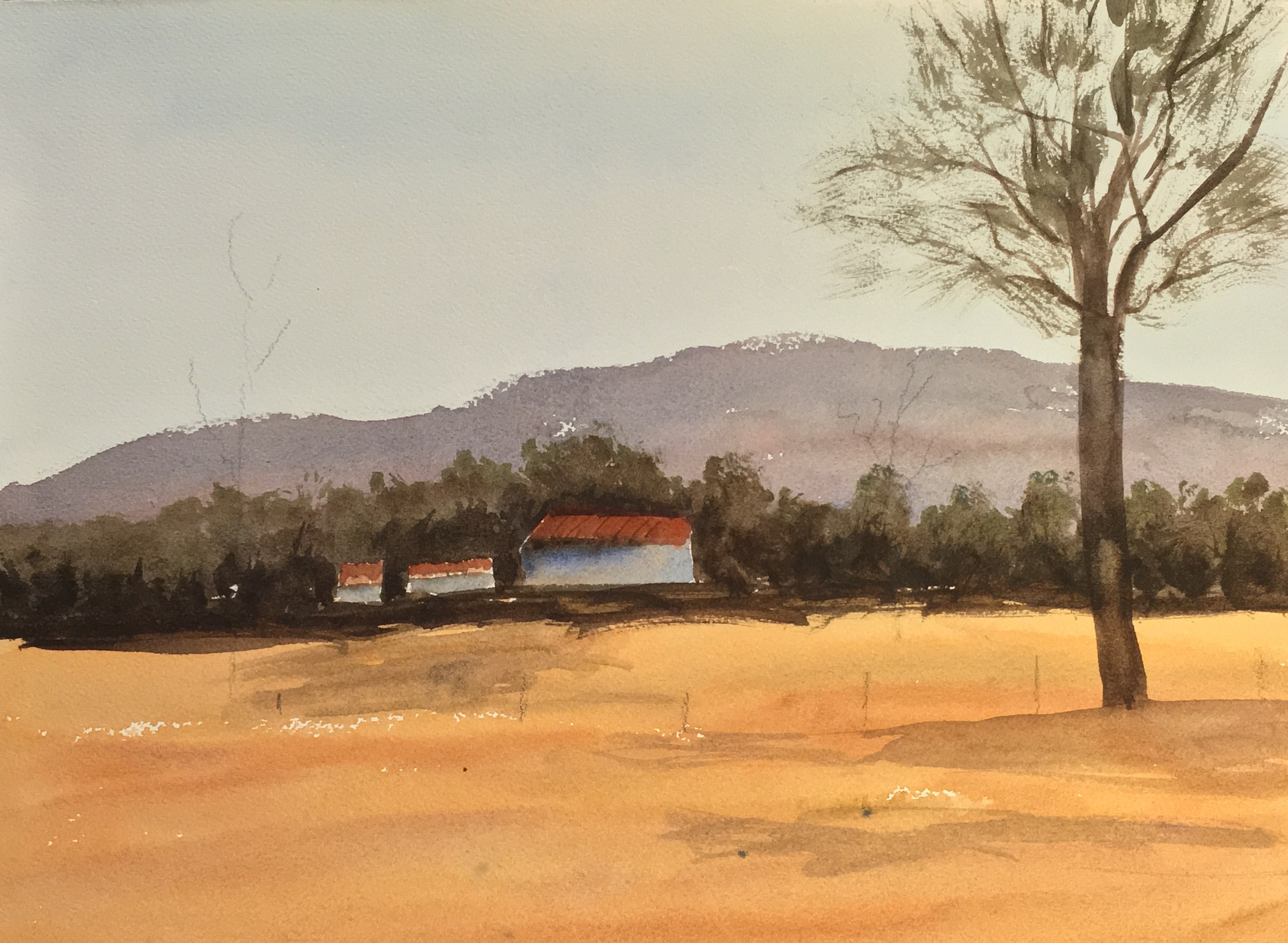 Landscape of rolling hills and three farm buildings in the distance